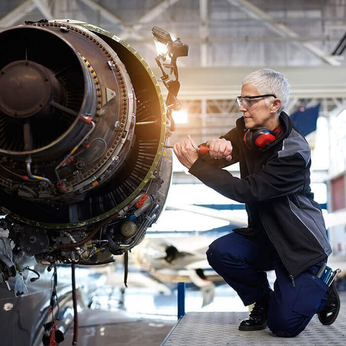 Mechanikerin führt Wartungsarbeiten an einem Jet-Triebwerk durch