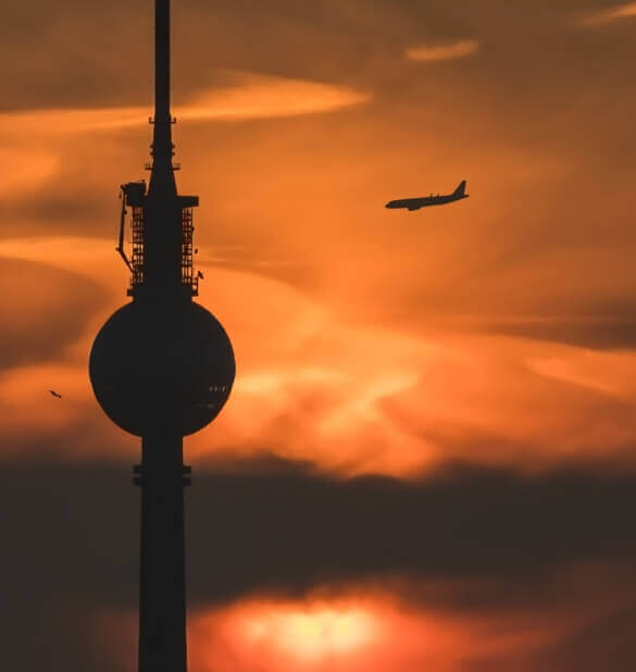 Berliner Fernsehturm bei Dämmerung mit Flugzeug im Hintergrund